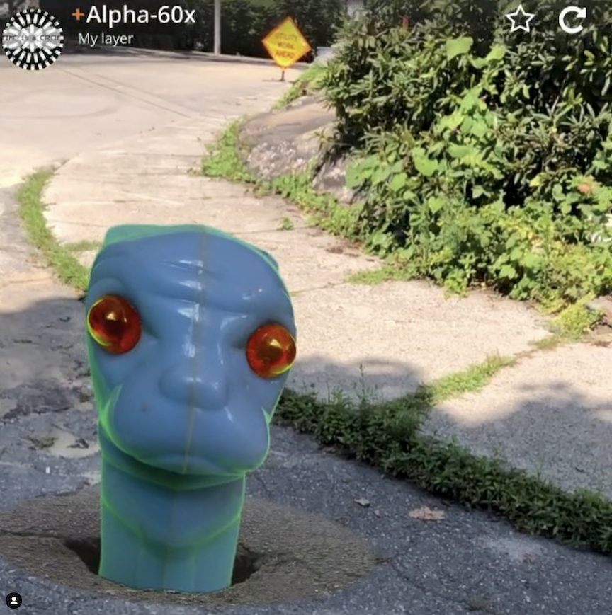 Blue creature emerging from pavement in augmented reality