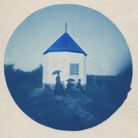 Earliest known photo of the Beverly Powder House with three women in black dresses with parasols